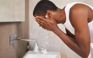 A young man washing his face.